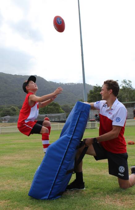 UP THERE: Camden Haven Bombers junior Max Fellowes assisted by Sydney Swans player Will Hayward at the recent coaching clinic in Laurieton.