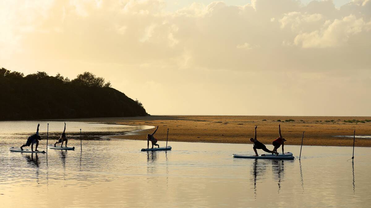 Serenity: A stunning sunrise over Lake Cathie with a yoga group meditating on stand up paddle boards.