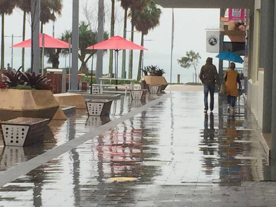 All alone: Two pedestrian hugging the side of the foothpath during a downpour of rain on Monday. Photo: Peter Daniels