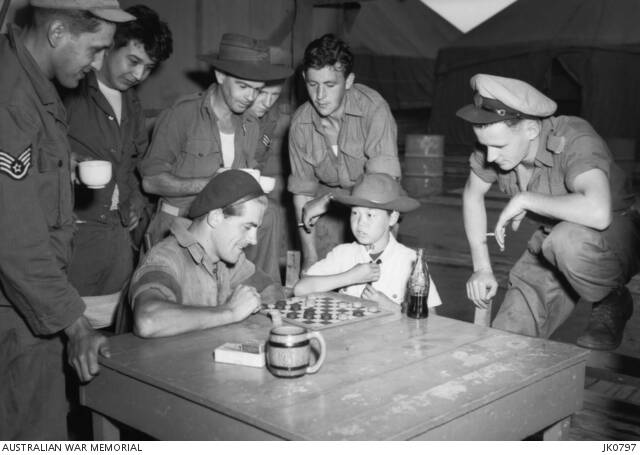 Forgotten war: Korean youngster "Jimmy" plays draughts with Leading Aircraftman Lance Lee of No. 77 Squadron, RAAF, who was part of the No. 77 Squadron headquartered at RAAF Base Williamtown. The photo was taken at Kimpo, South Korea om 1953. Photo: Australian War Memorial JK0797