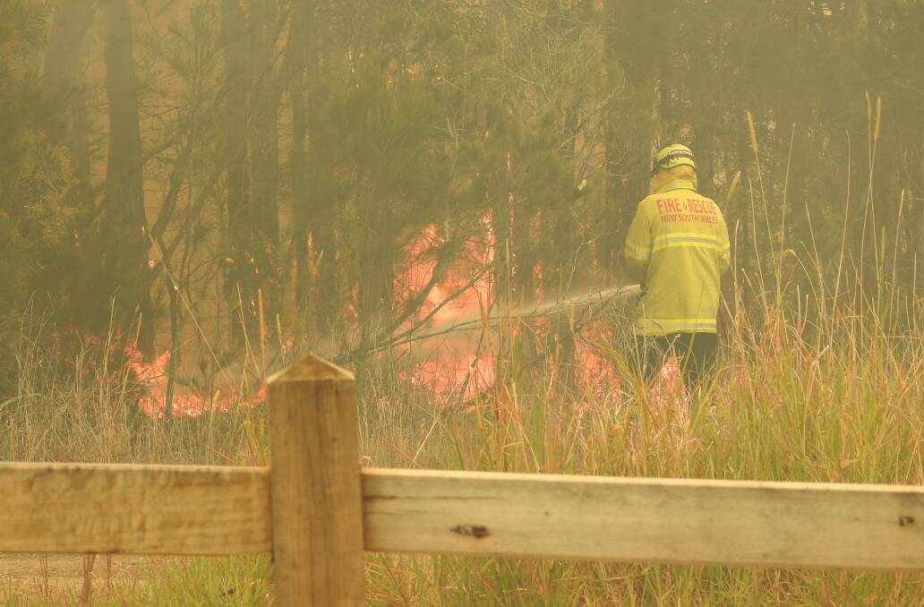 A Rural Fire Service volunteers fights a fire near homes in College Rise in Thrumster last Friday.