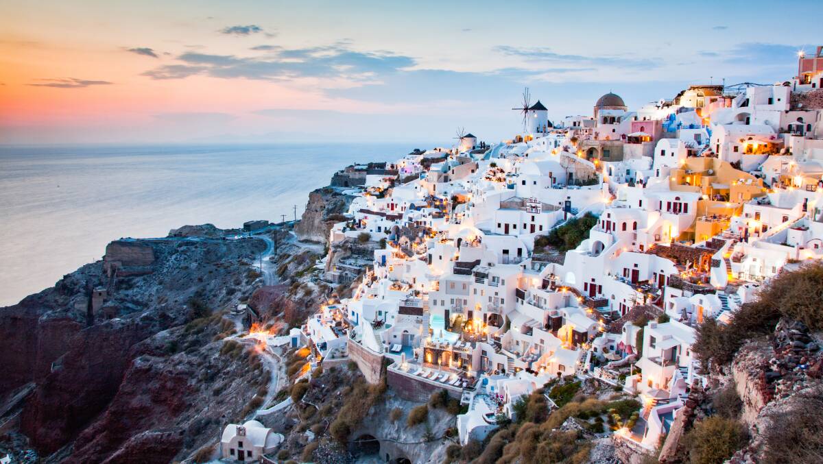 Beautiful Oia town on Santorini island, Greece: traditional white architecture and Greek orthodox churches with blue domes over the Caldera.
