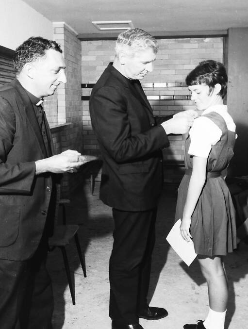 Congratulations: Father Leo Donnelly pins a badge on St Joseph's school captain Denise Sharkey watched on by Father Mills, 1970.