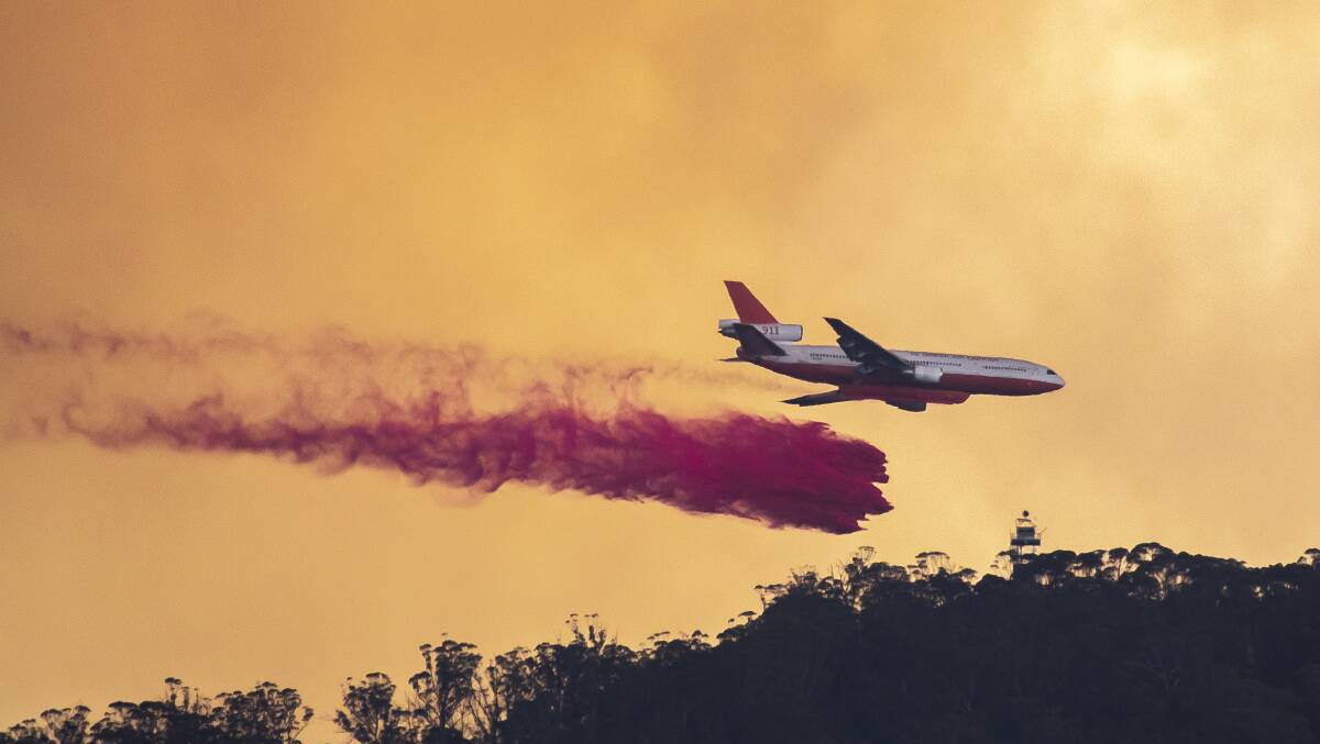 An aircraft drops fire retardant on Mt Tennant earlier in the year. Picture: Sitthixay Ditthavong