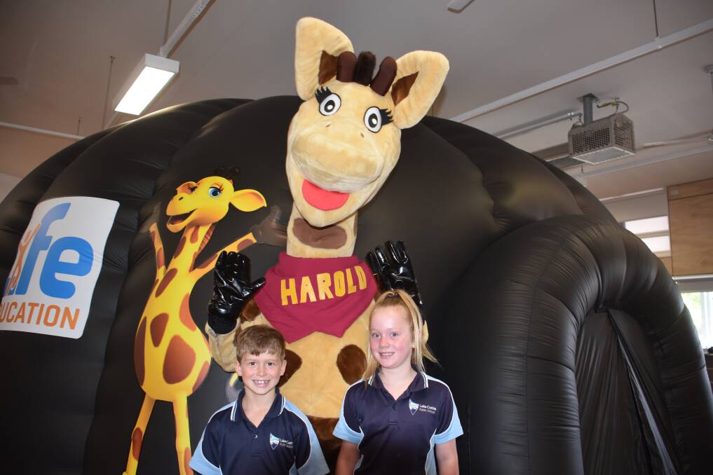 Happy Harold: Lake Cathie Public School students Locke Williamson and Jorjah Warwick with Healthy Harold giraffe outside the new pop-up classroom. 