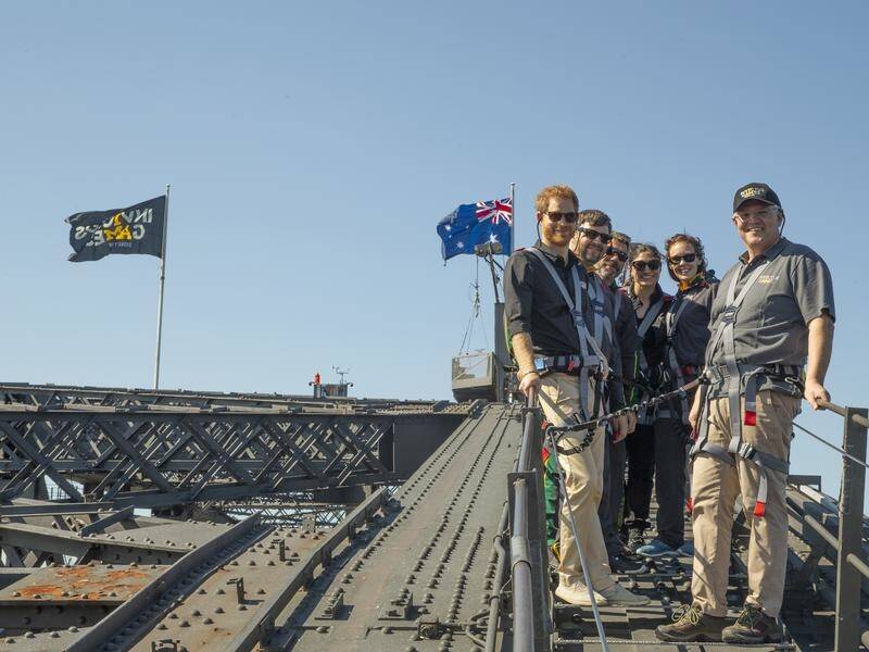 Prince Harry has scaled Sydney's Harbour Bridge for the raising of the Invictus Games flag.