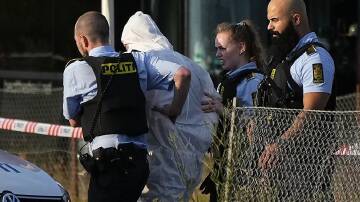 A person in a white DNA suit is taken away by police after the mass shooting in Copenhagen.